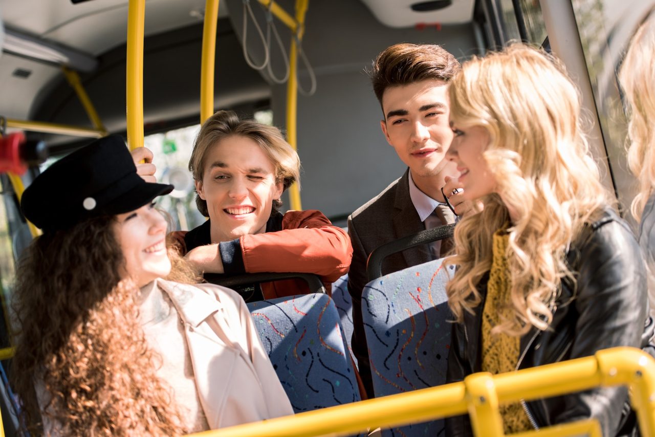 Happy young friends talking while sitting in city bus.jpg